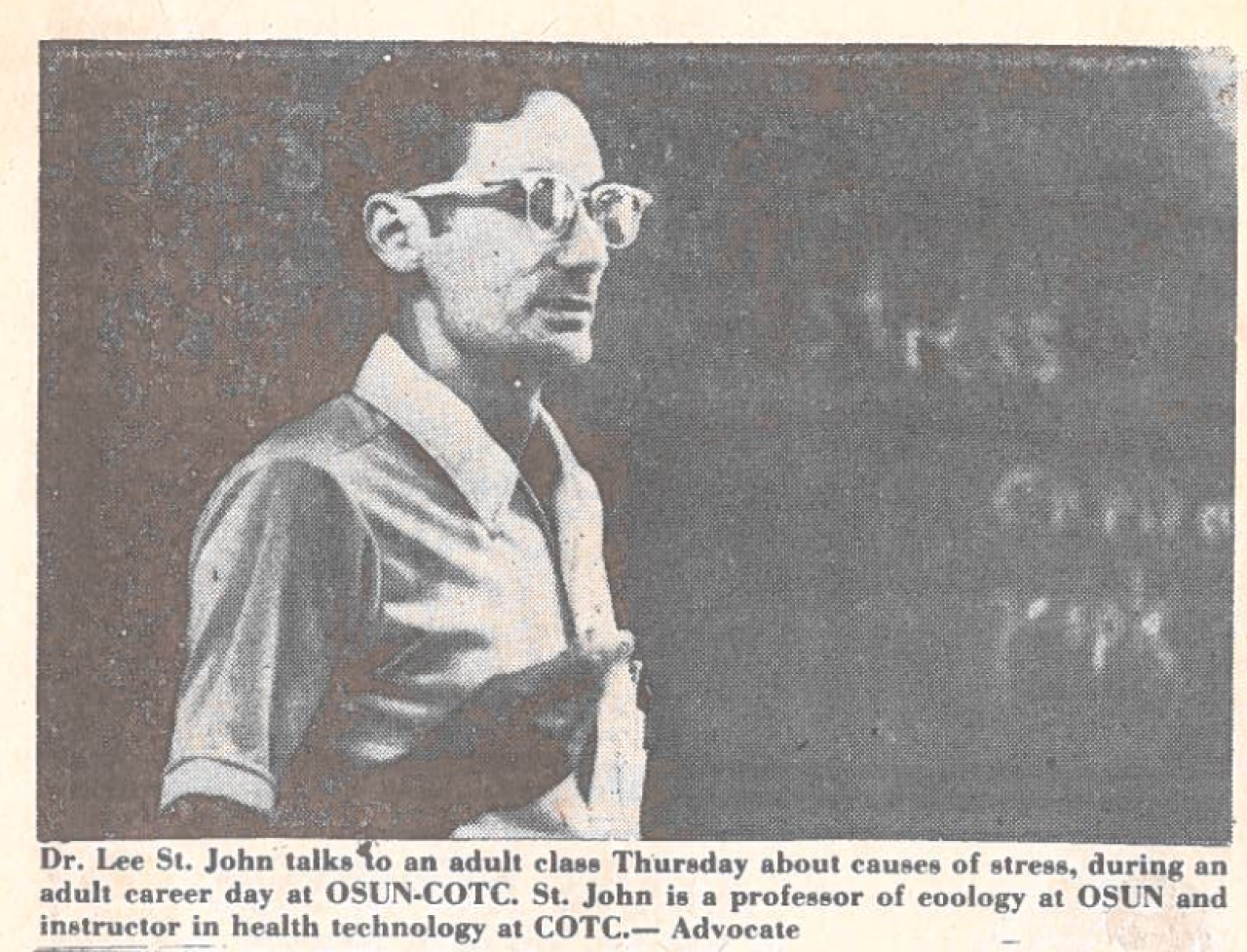 A newspaper clipping shows Lee St. John standing in front of a chalkboard looking into a classroom.