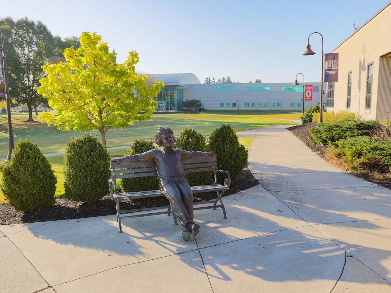 A bronze statue of Albert Einstein seated on a bench. 
