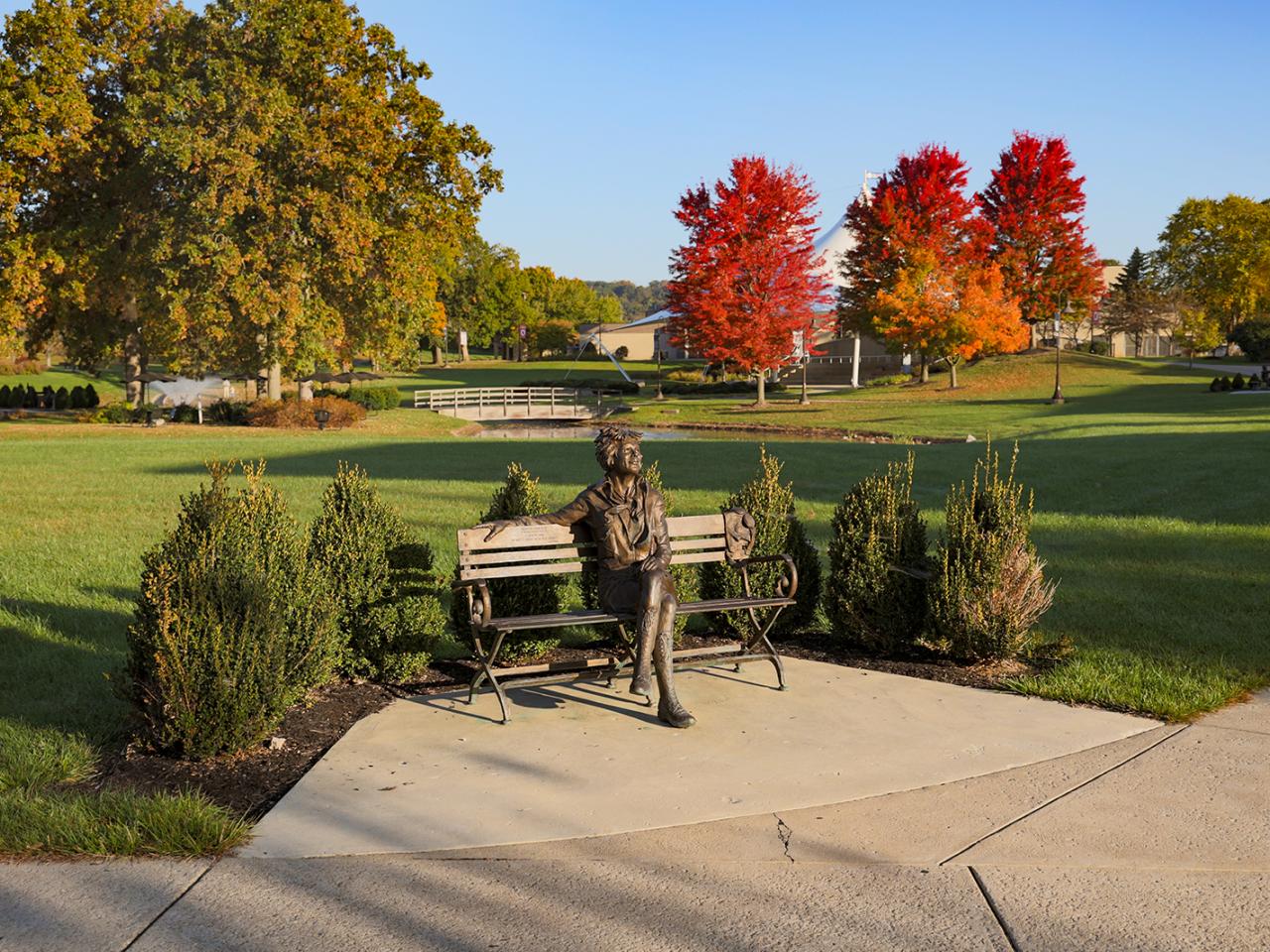 A bronze statue of Amelia Earhart seated on a bench. 