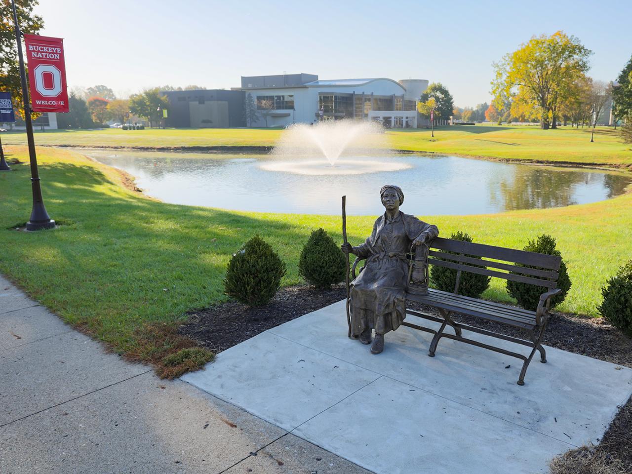 A bronze statue of Harriet Tubman seated on a bench