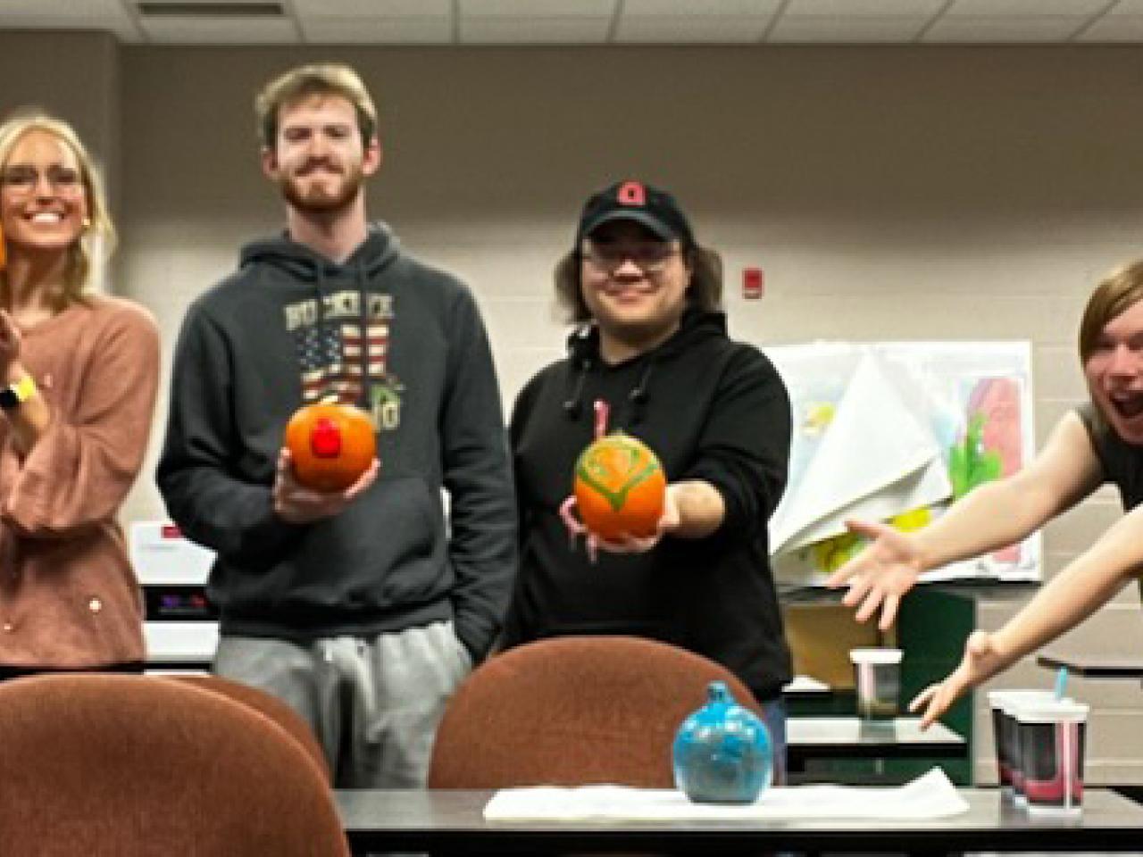 Four step student show off pumpkins they decorated.