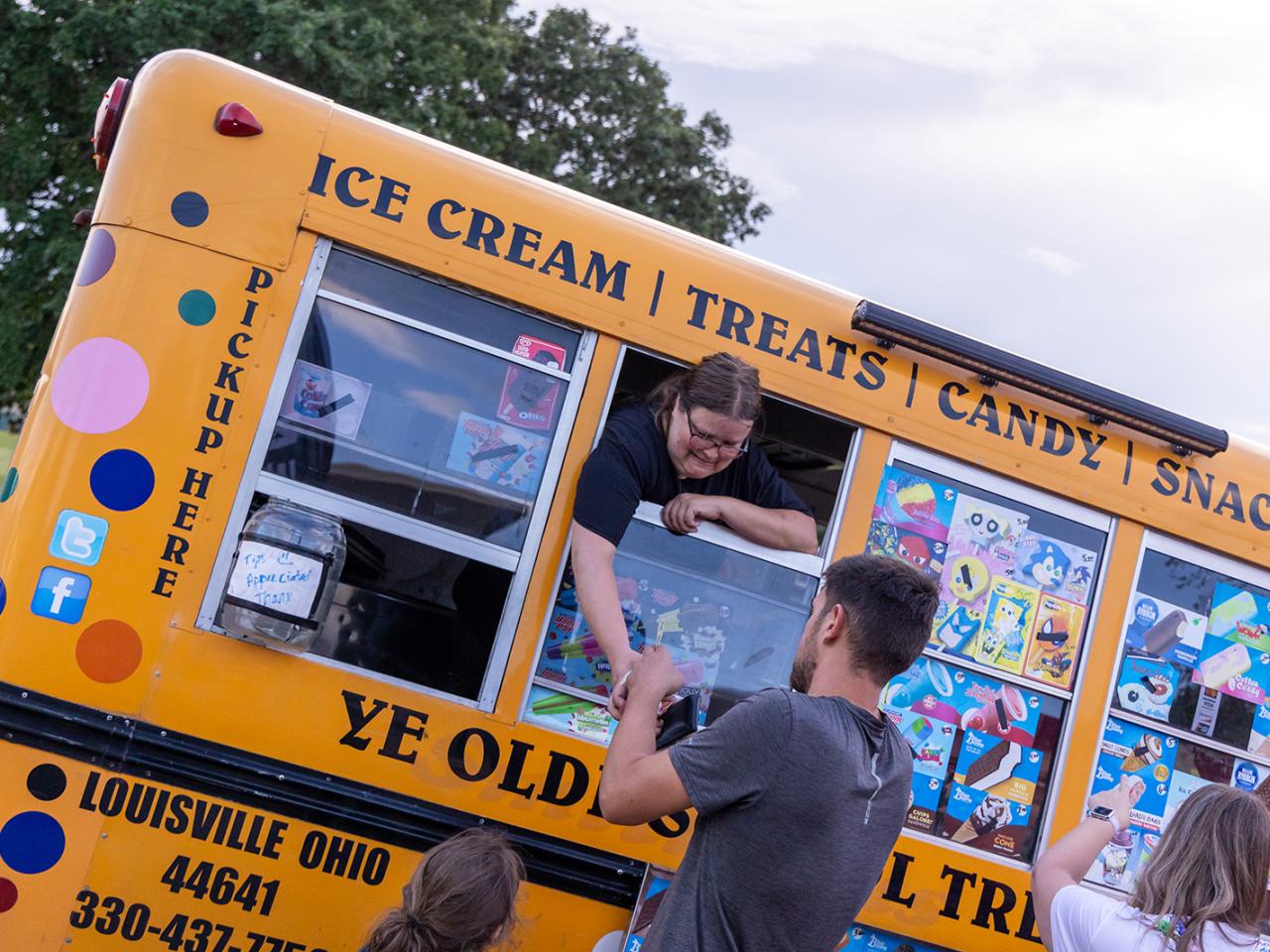 A man buys a frozen treat from a food truck. 
