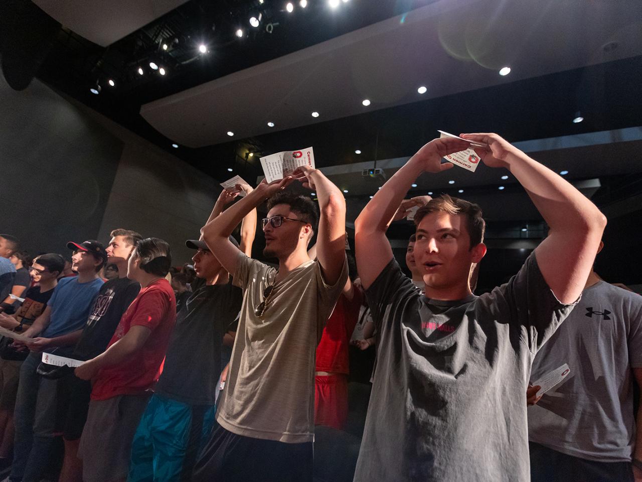 Students in the crowd form the letter O with their arms above their head.