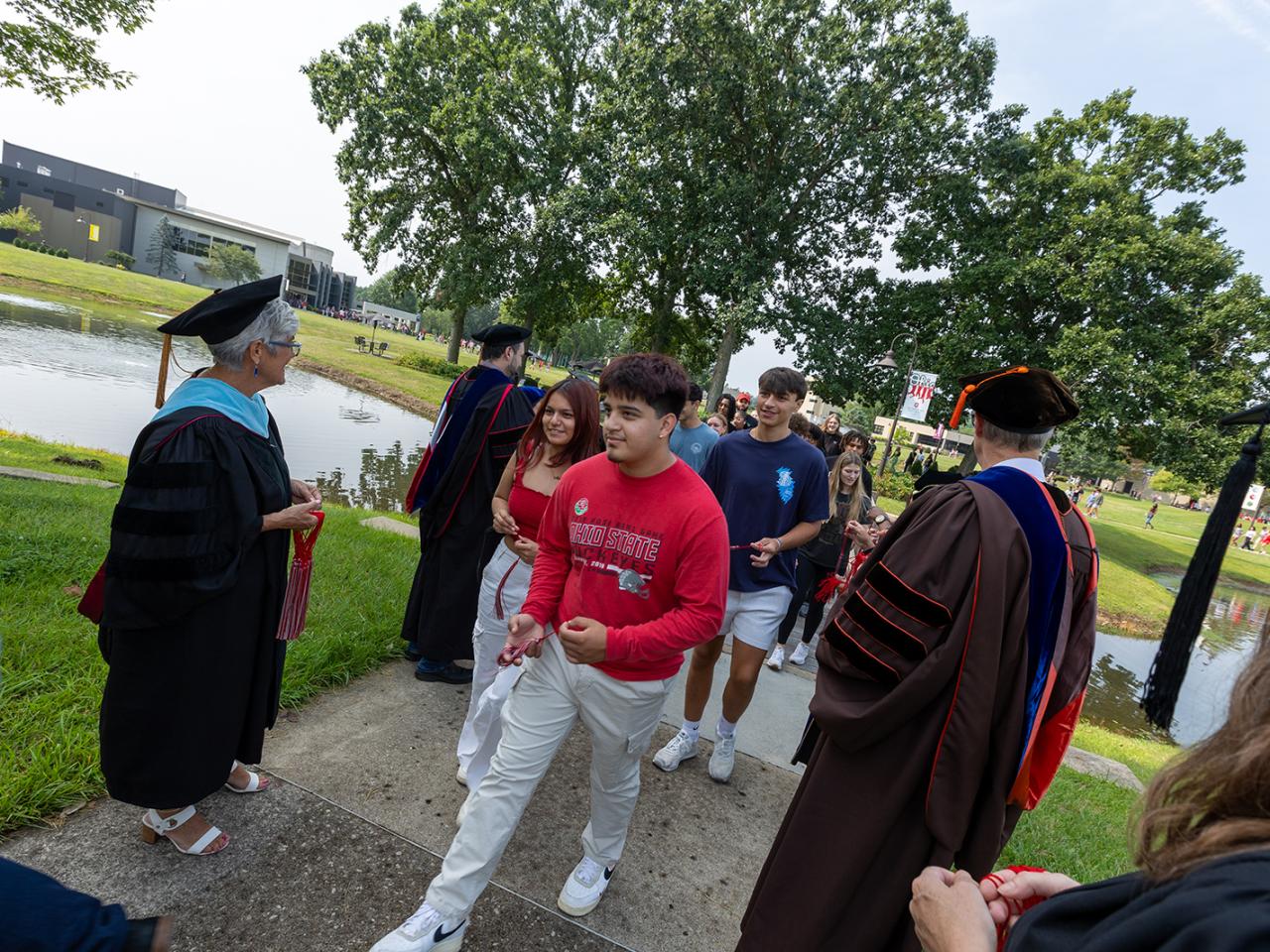 Students walk through faculty awaiting them on the bridge for the traditional bridge walk.