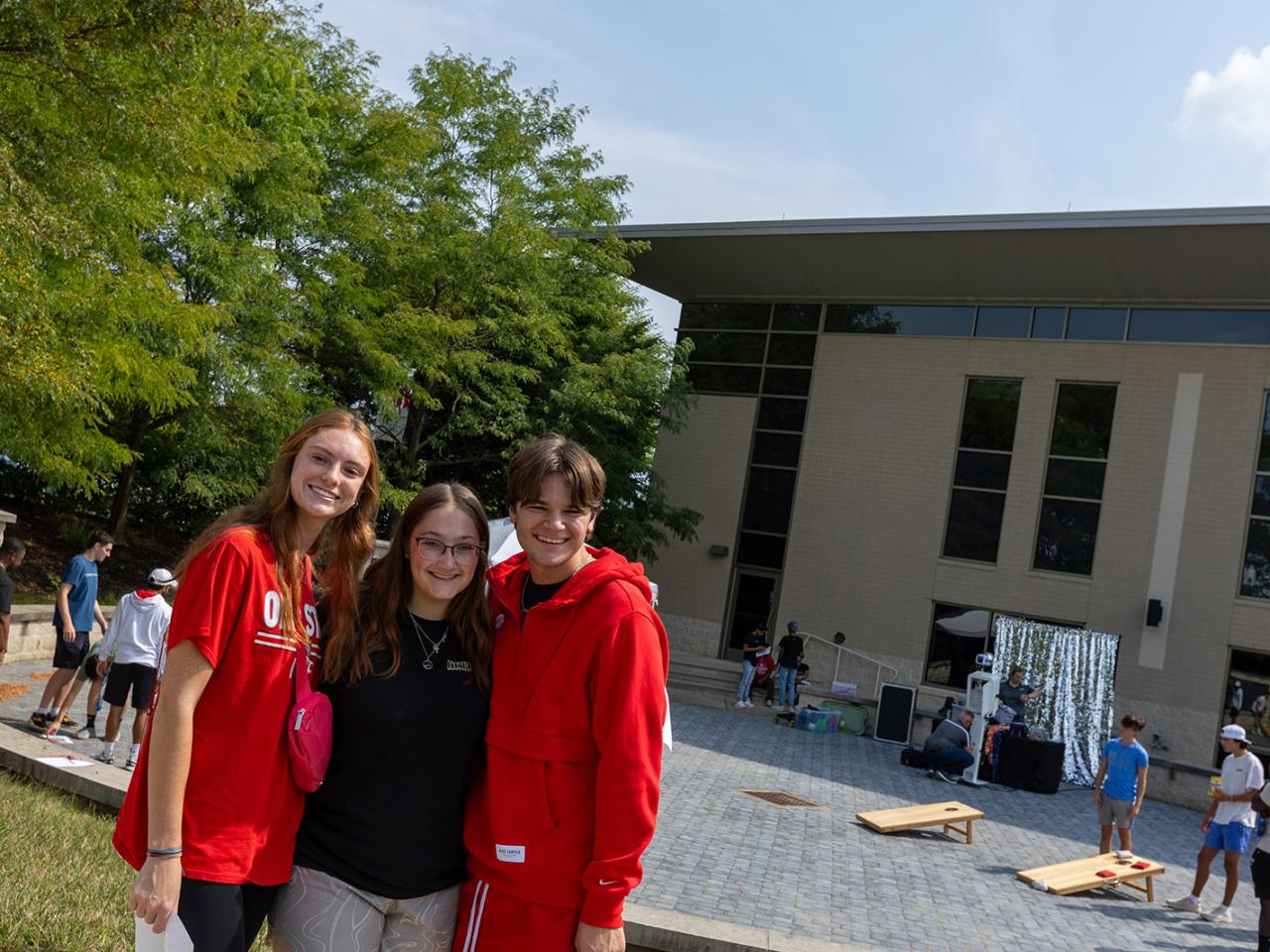Three students huddle together to pose for a picture during the post-Convocation lunch outside the Warner Center.
