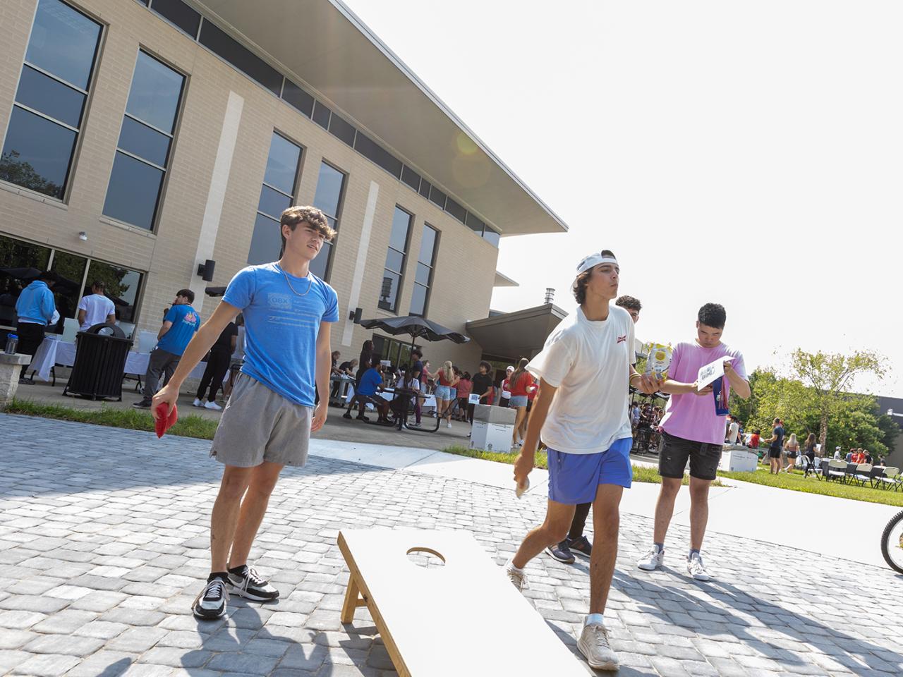 Students play a game of cornhole during the post-Convocation lunch on the patio of the Warner Center.