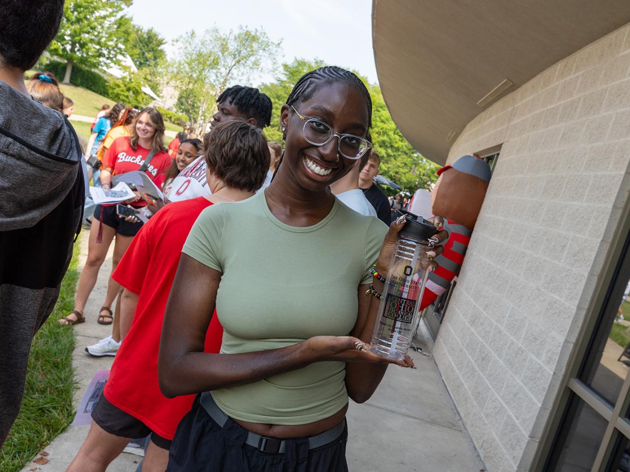 A female student smiles for the camera among a crowd of students during the post-Convocation lunch on the patio of the Warner Center.