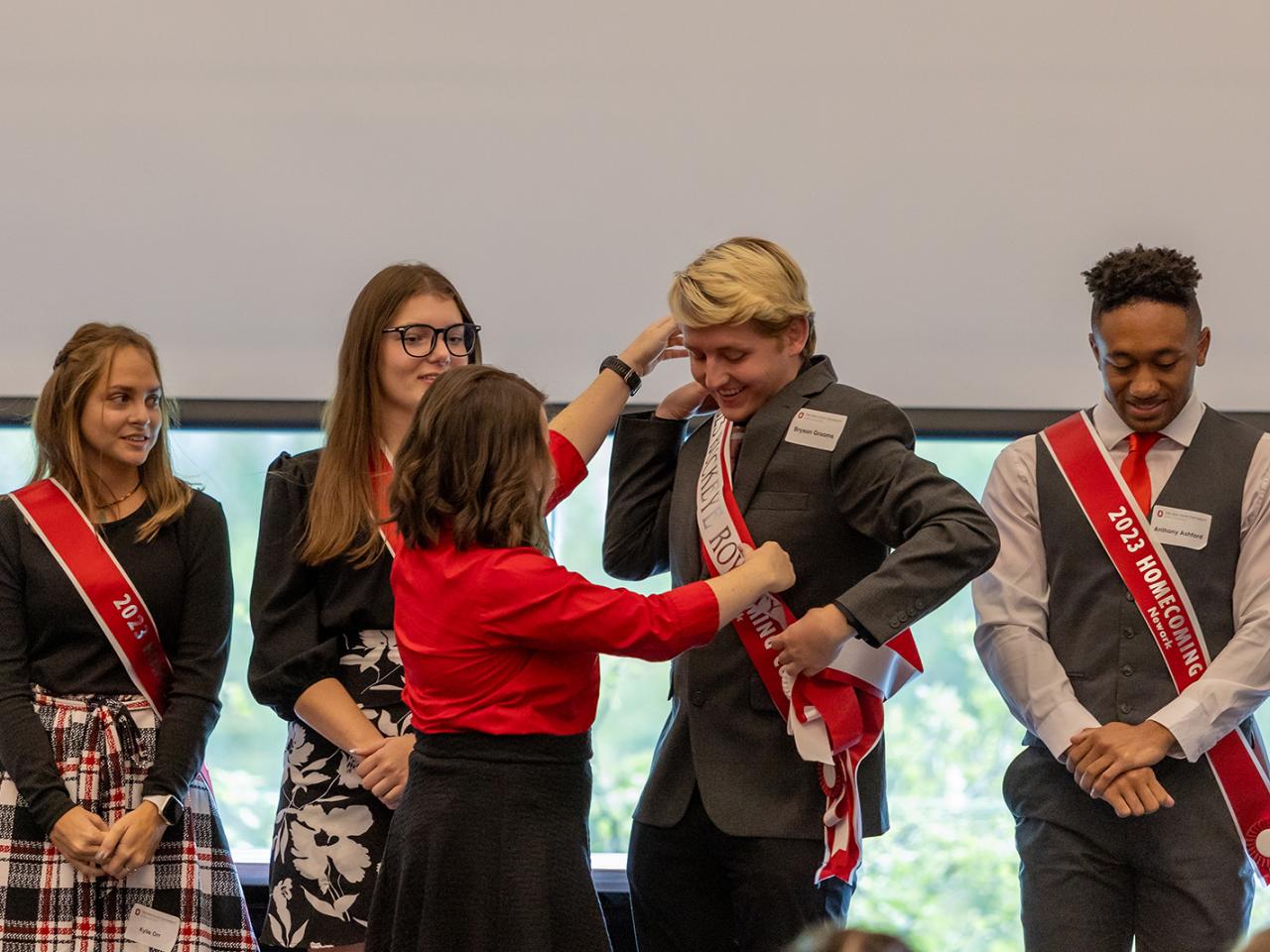 A staff member places the royal Buckeye sash on Bryson Grooms.