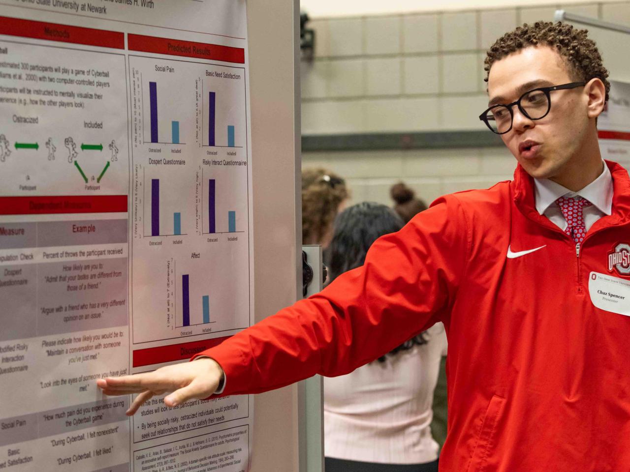 A student points to his research poster during a presentation at the Student Research and Scholarship Forum.