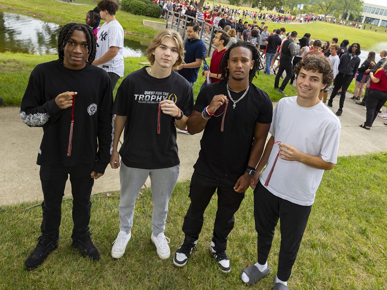Four students hold their tassels they received as part of the Convocation bridge walk tradition.