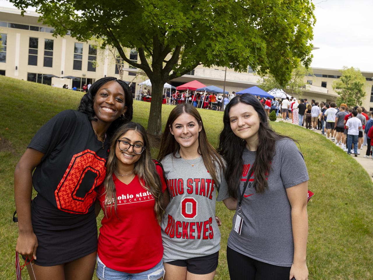 Four female students huddle together for a photo on the campus lawn.