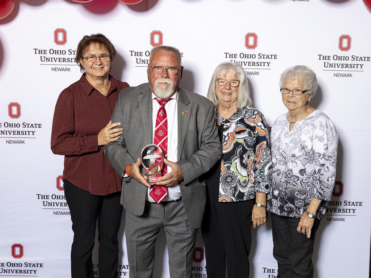 Kenneth Yeager holds his award for Distinguished Alumni surrounded by family members.