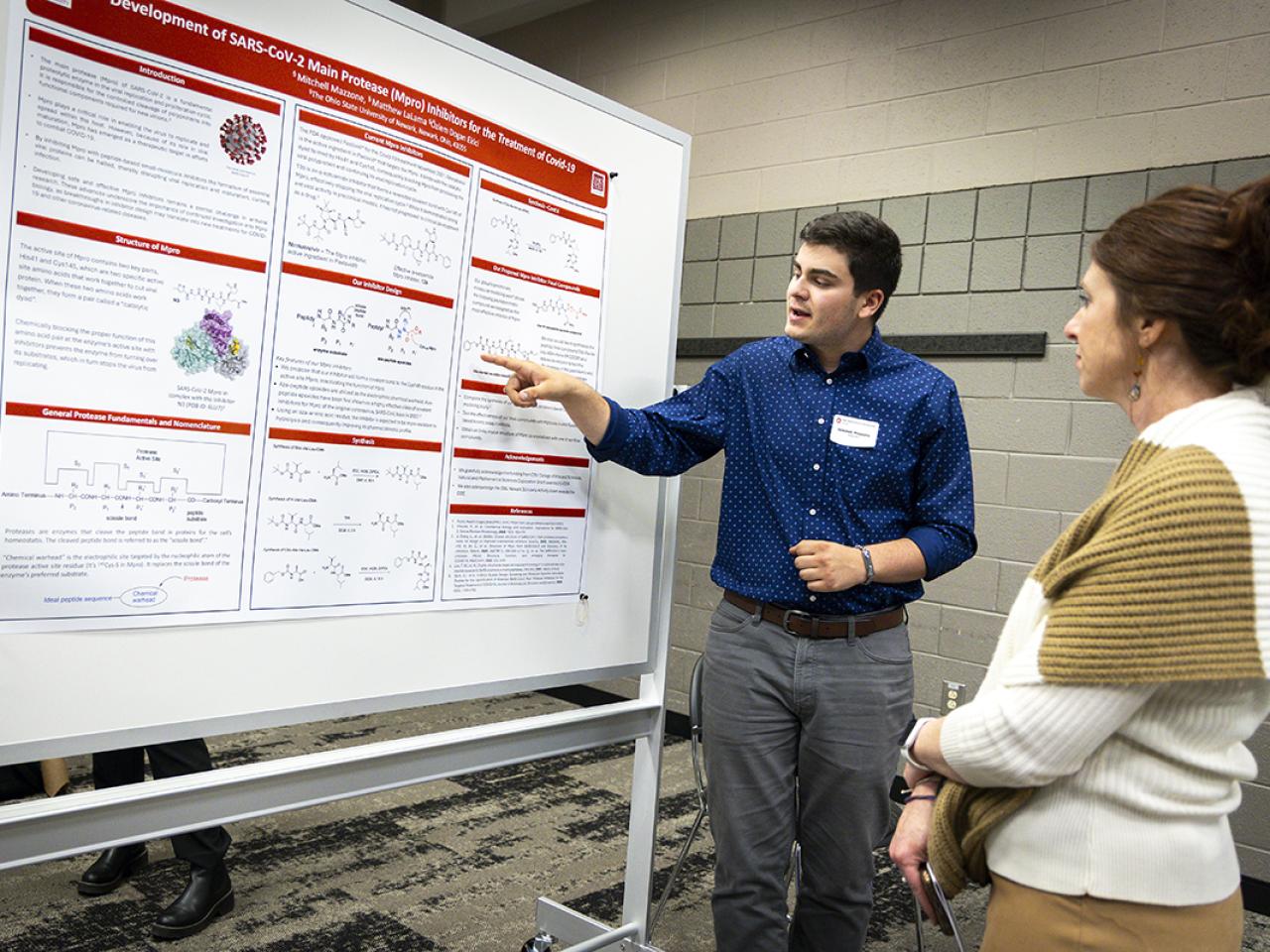 A student points to his research poster during a presentation at the Student Research and Scholarship Forum.