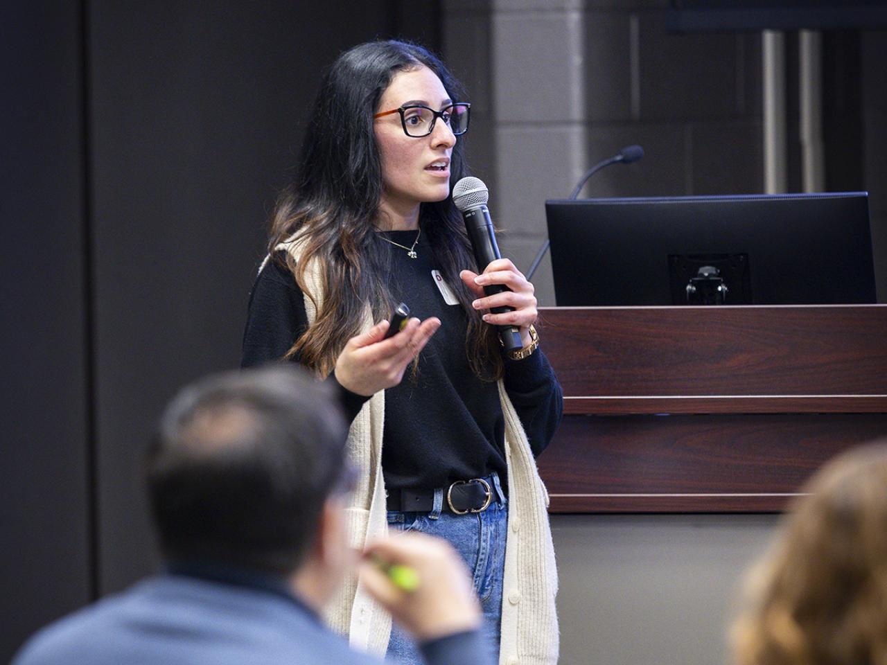 A student speaks into a microphone in front of a crowd of people.