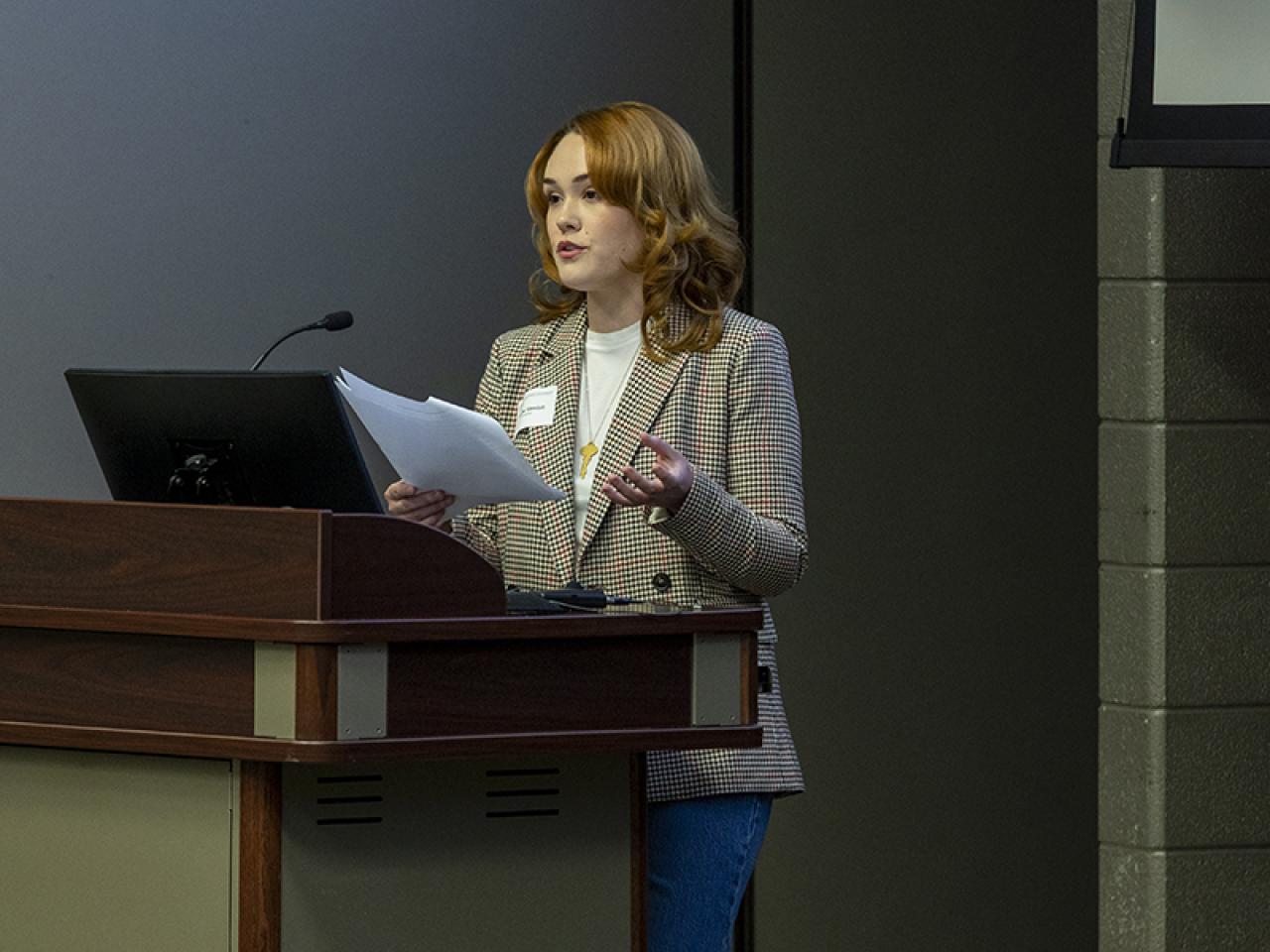 A student stands at podium speaking about her research.