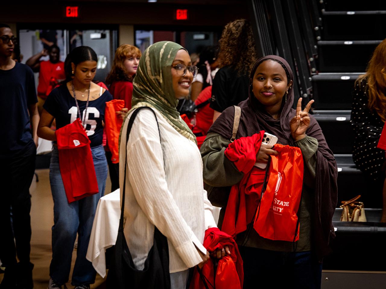 Two student entering the gymnasium stop to smile for the camera during Convocation.