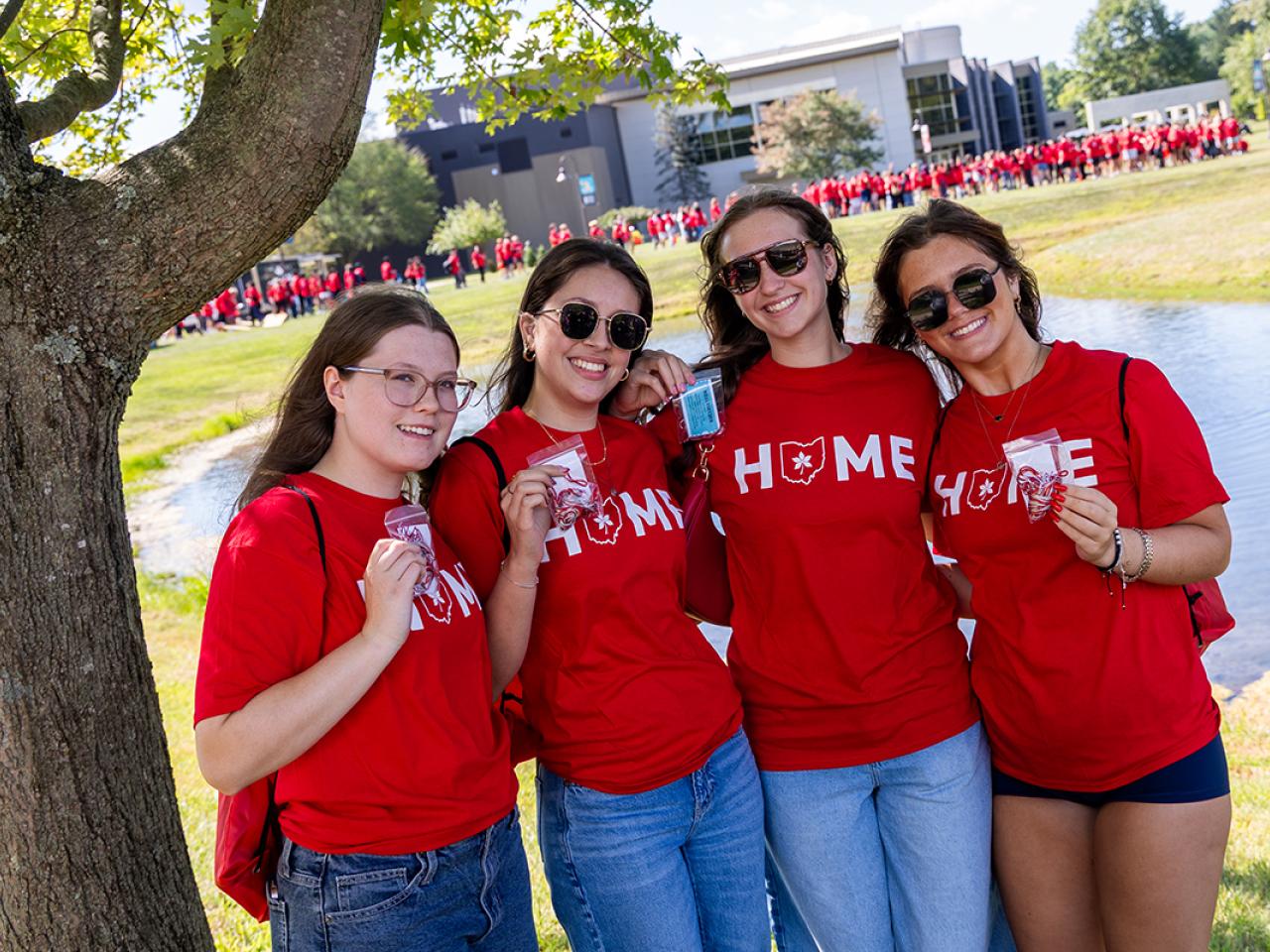 Four students stand together holding up their scarlet and gray tassels they just received as part of the Convocation tradition.