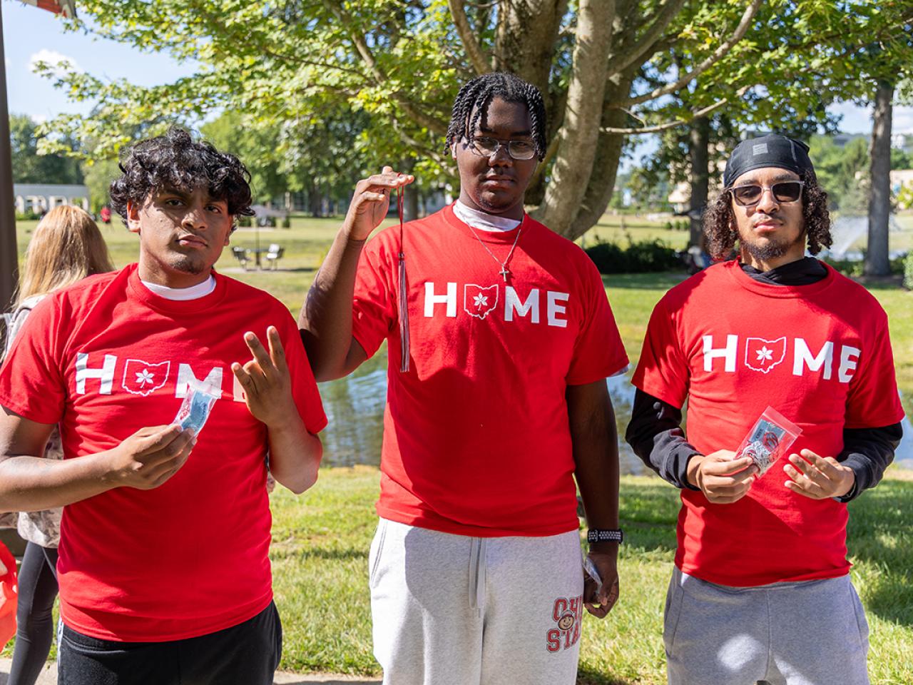 Three students hold up their scarlet and gray tassels they just received as part of the Convocation tradition.