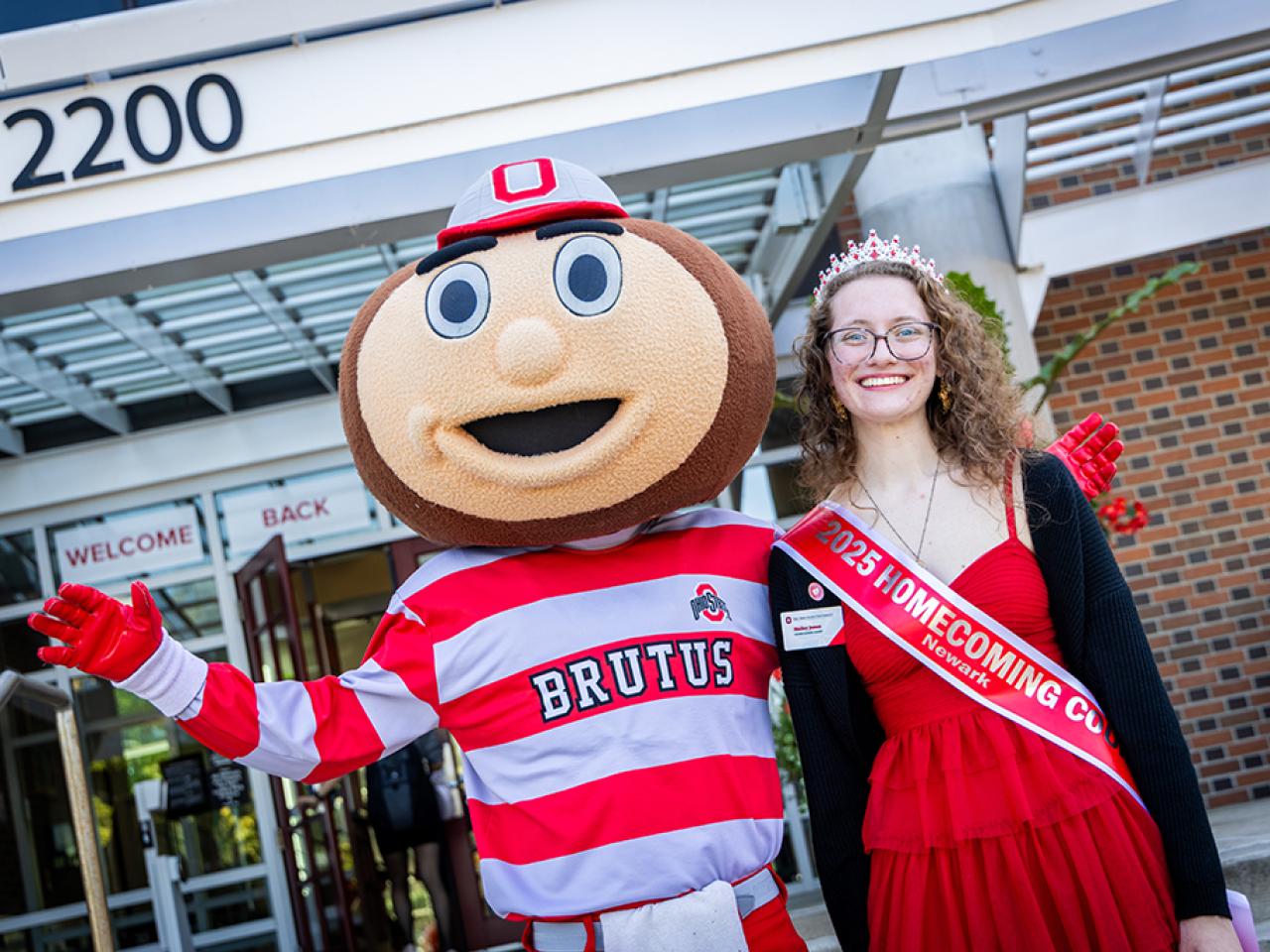 Ohio State Newark Homecoming Court member Hailey Jones with Brutus Buckeye outside the Longaberger Alumni House for the regional campus Homecoming recognition ceremony.