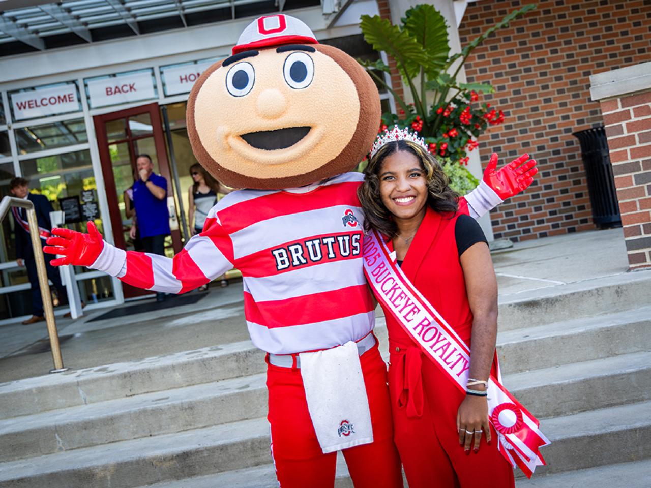 Ohio State Newark Homecoming Court member Nia Coats with Brutus Buckeye outside the Longaberger Alumni House for the regional campus Homecoming recognition ceremony.