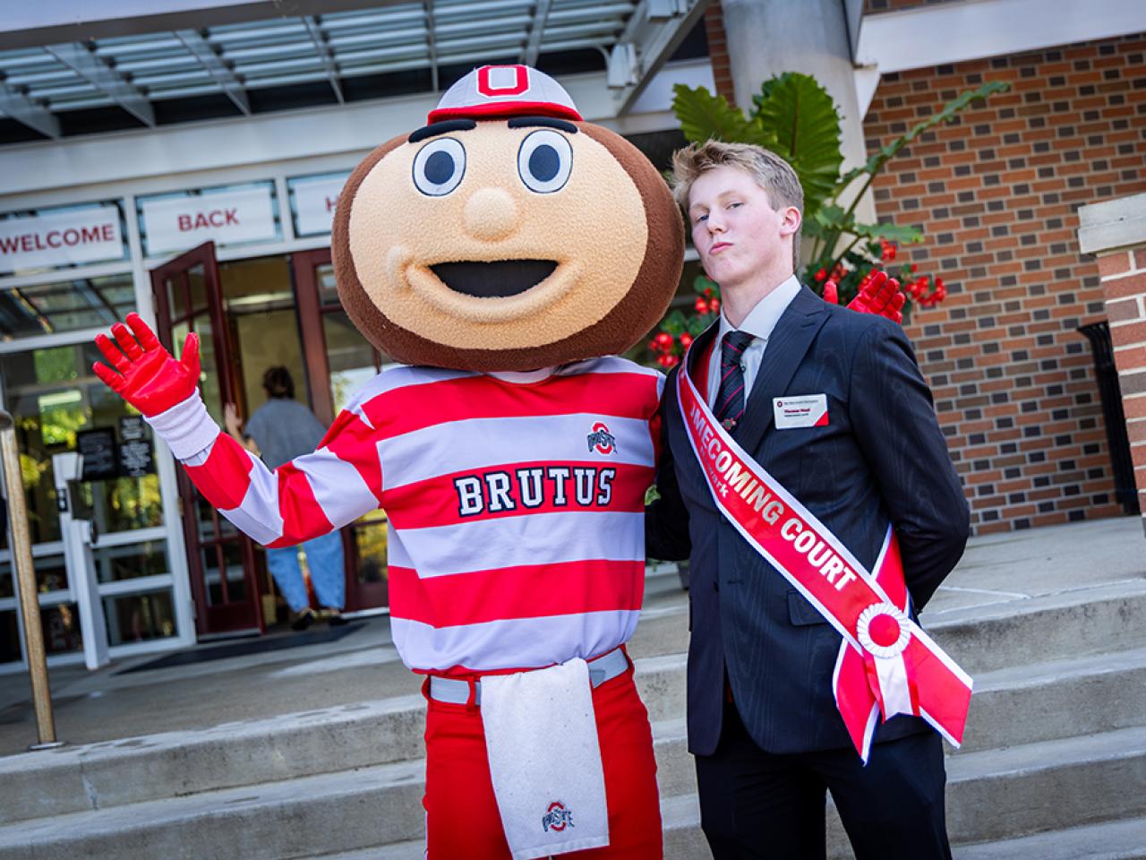 Ohio State Newark Homecoming Court member Thomas Maul with Brutus Buckeye outside the Longaberger Alumni House for the regional campus Homecoming recognition ceremony.