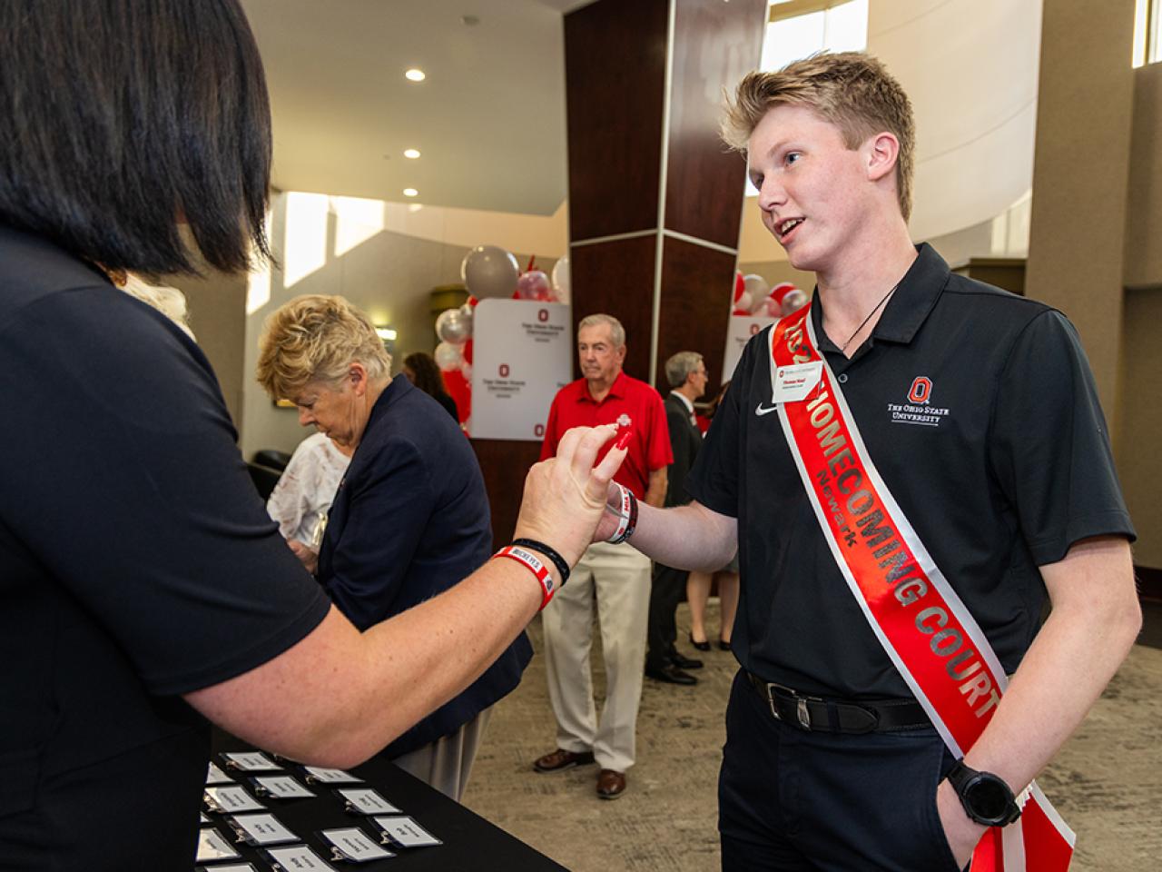 A student on the Homecoming court shakes hand with a guest at the alumni Homecoming dinner.