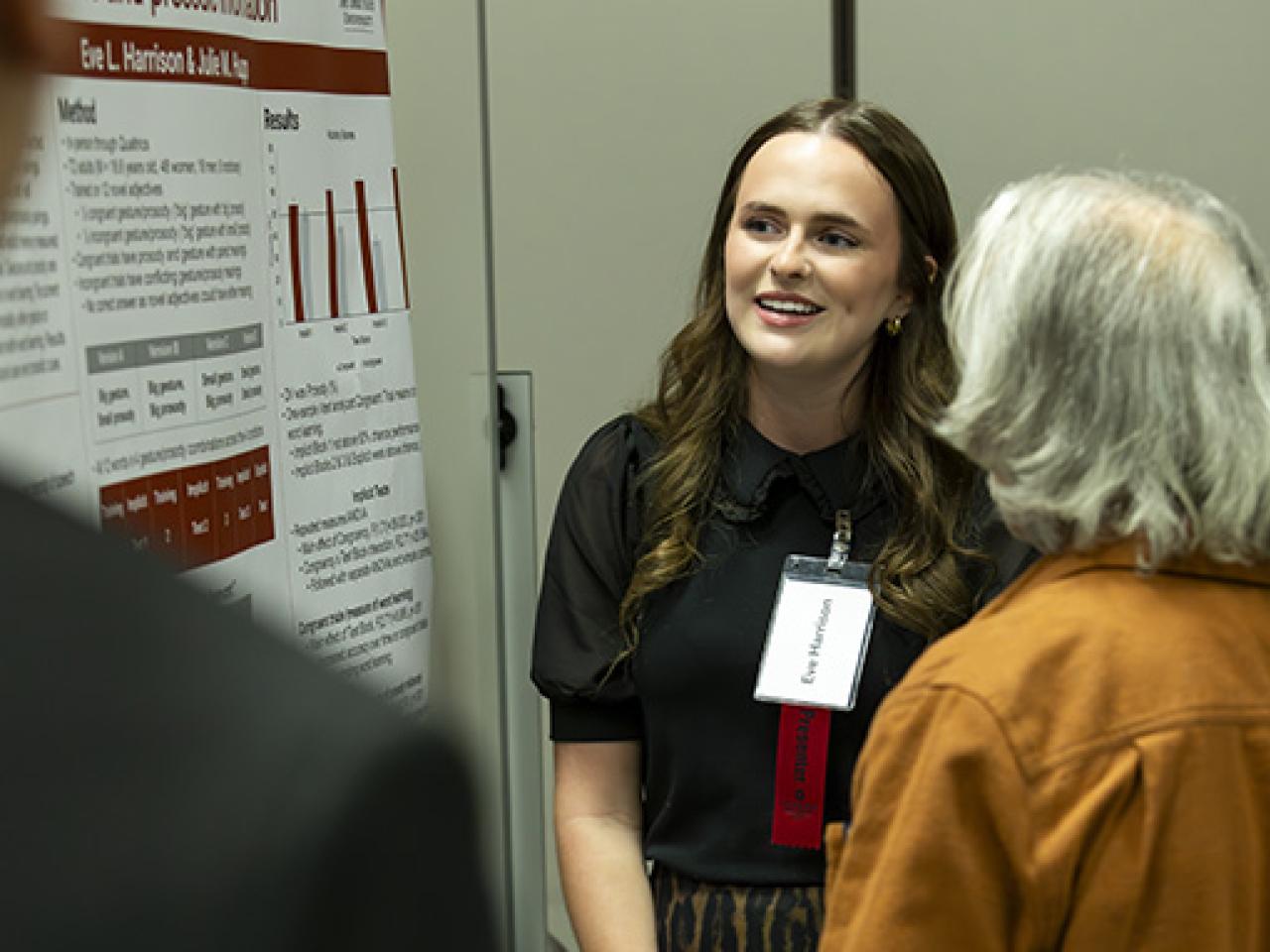 Eve Harrison looks at her poster as she presents to attendees of the Student Research and Creative Inquiry Forum.