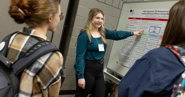 A student presents her research poster to an audience.