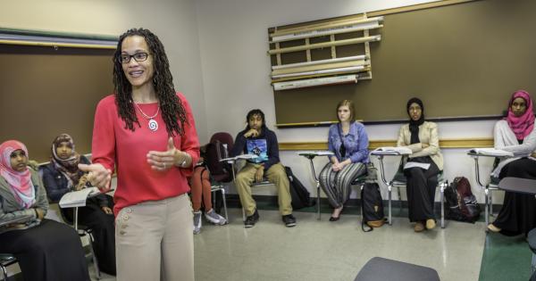 Associate Professor stands amid a semi-circle of students while teaching class.