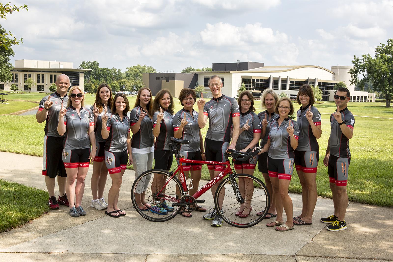 Thirteen member of Team Buckeye - Rolling for a Cure stand behind a bicycle on the Newark campus.