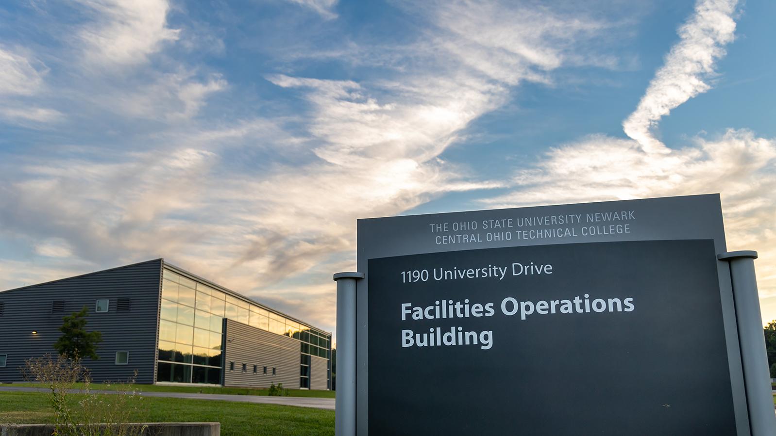 An outdoor sign in front of a building reads Facilities Operations Building.