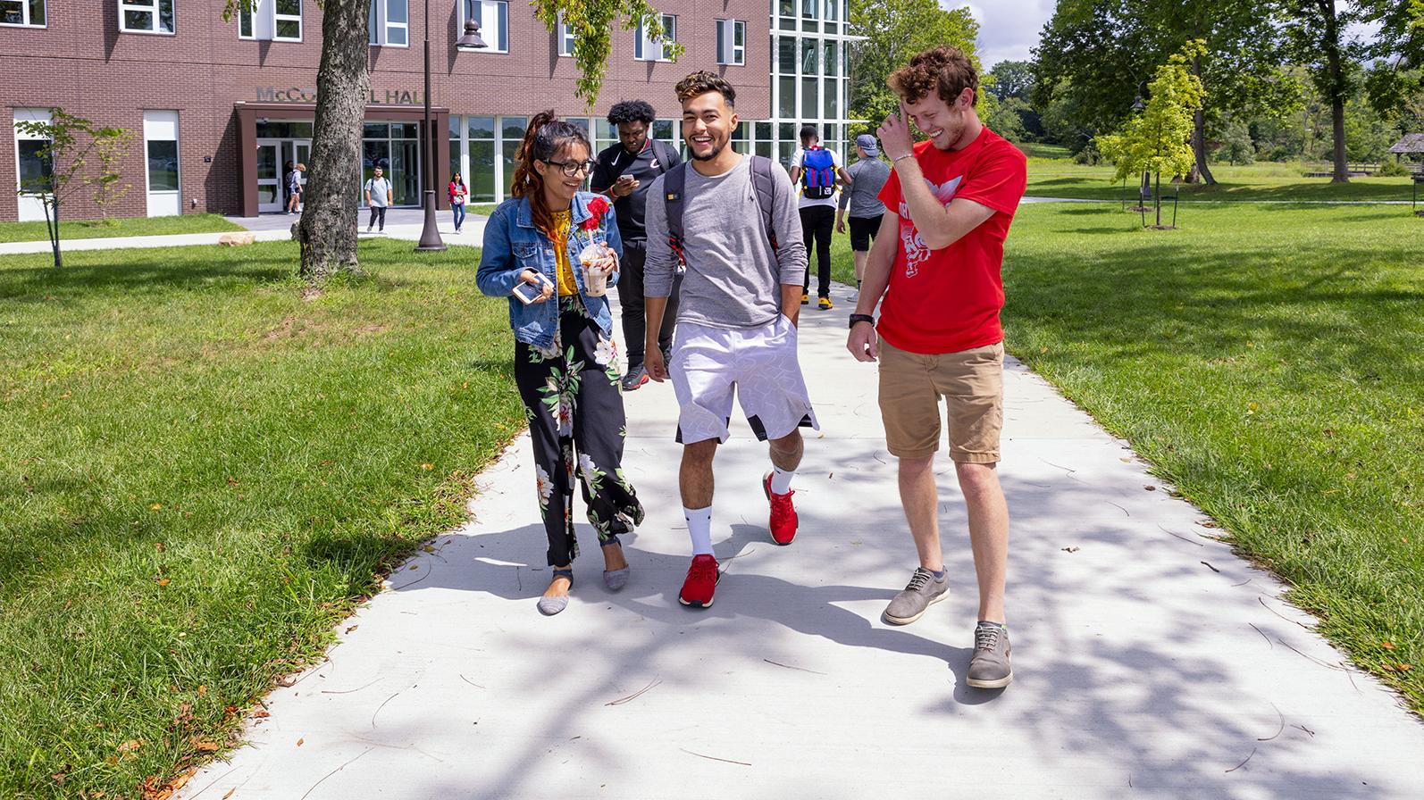 Three students walk away from McConnell Hall laughing and smiling. 