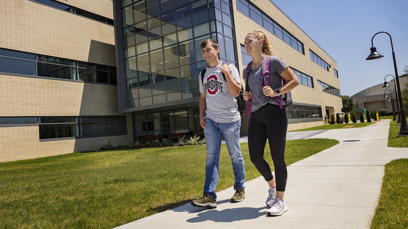 Two students walk on campus next to the Alford Center.