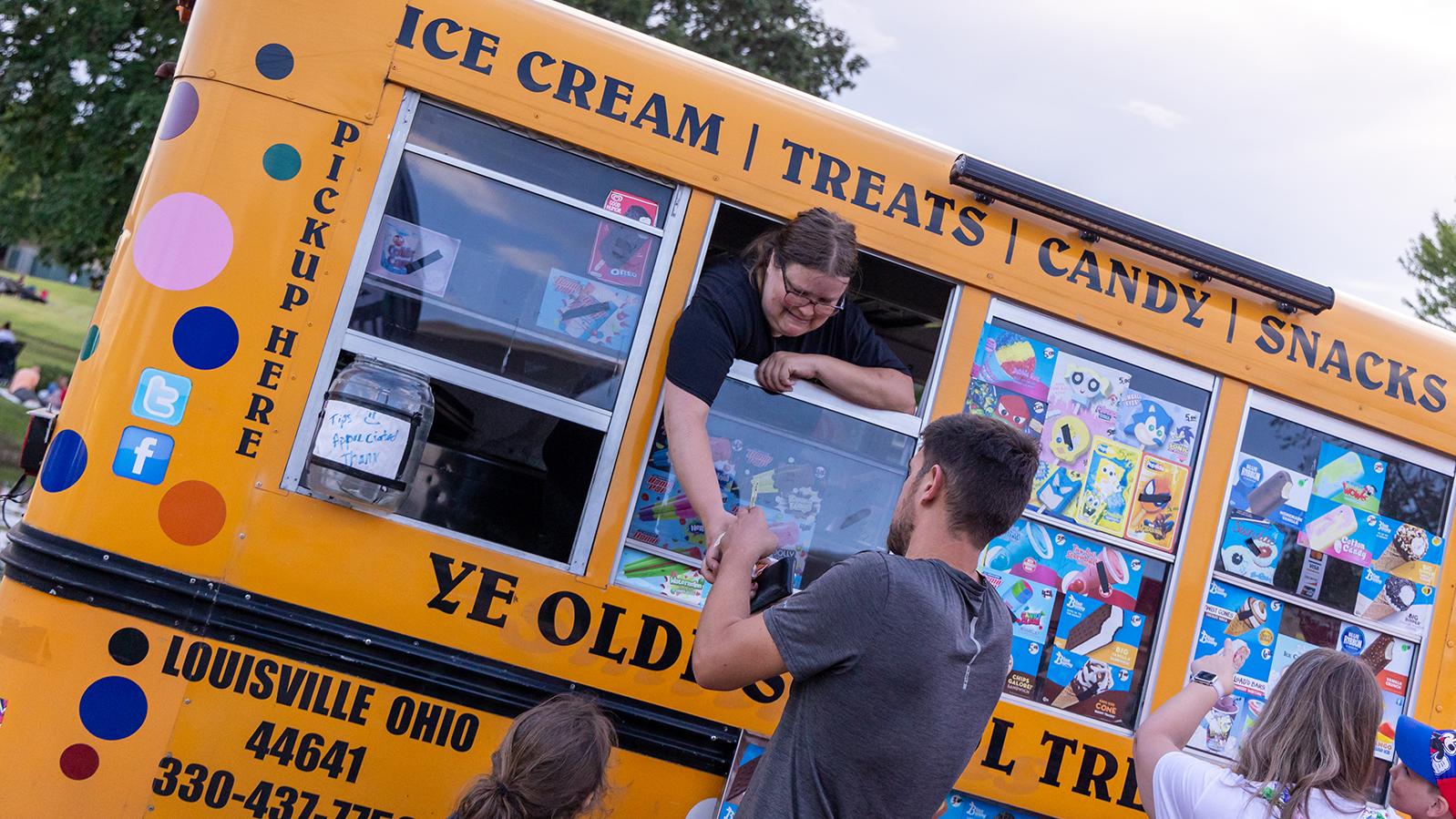 A man buys a frozen treat from a food truck. 