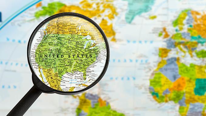 A magnifying glass reveals the United States on a world map.