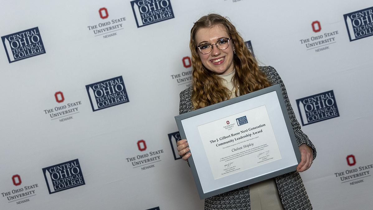 Portrait of Chelsea Shipley holding their award certificate.