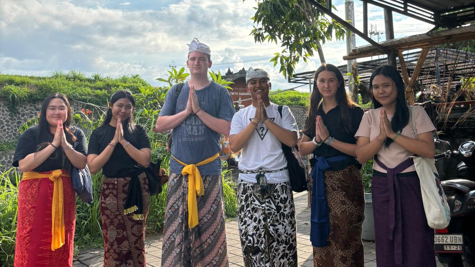 Education students in Bali stand outside wearing traditional Indonesian clothing.