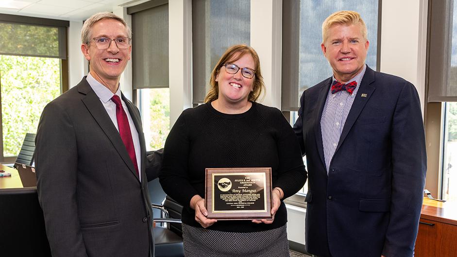 Amy Mangus holds a plaque standing between Ohio State Newark Dean and Director Matt Smith and COTC President John Berry.