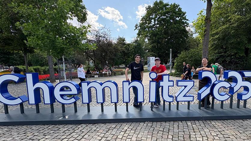 Students interning in Germany stand behind a sign that says Chemnitz, the name of a German city.