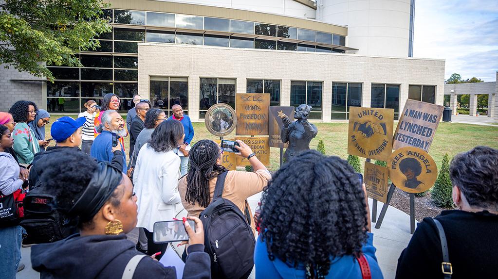 A crowd of people gather around the newly unveiled statue of Civil Rights activist Ella Baker on an event in October 2025.