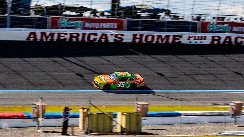 A yellow car driving fast on a racetrack. 