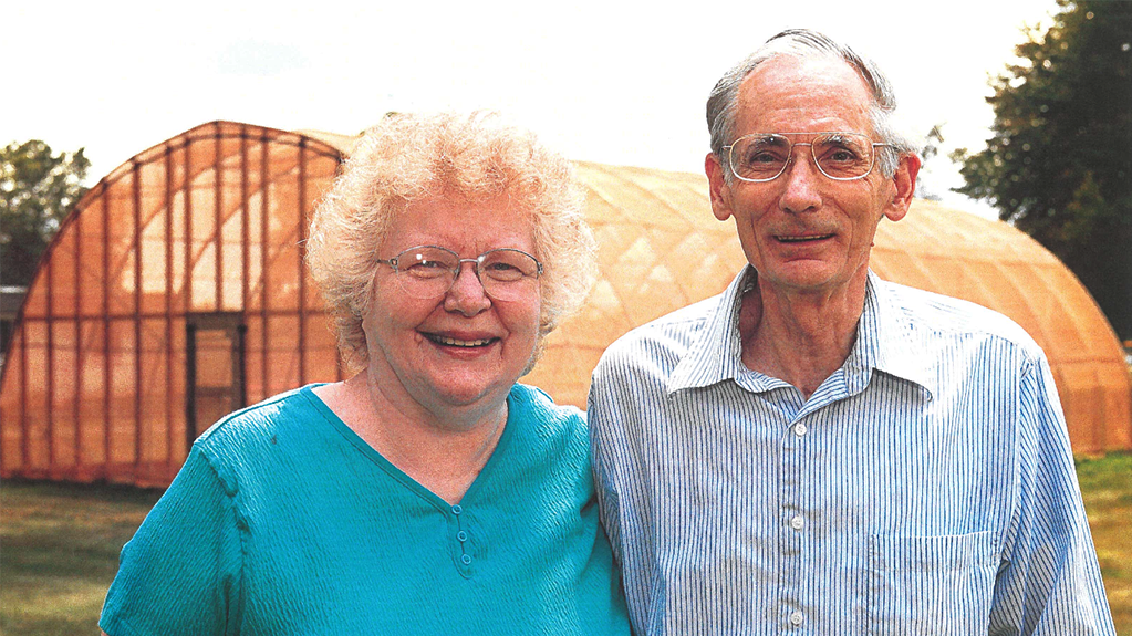 Portrait of Mary Ellen and Lee St. John outside of a greenhouse.