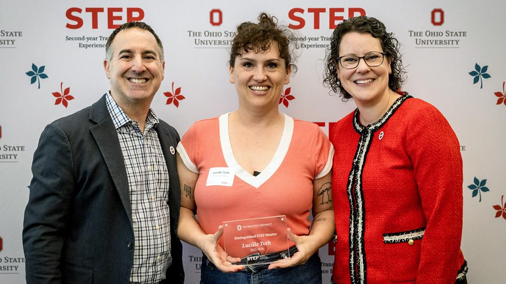 Lucille Toth poses with her Award in front of a STEP program banner.