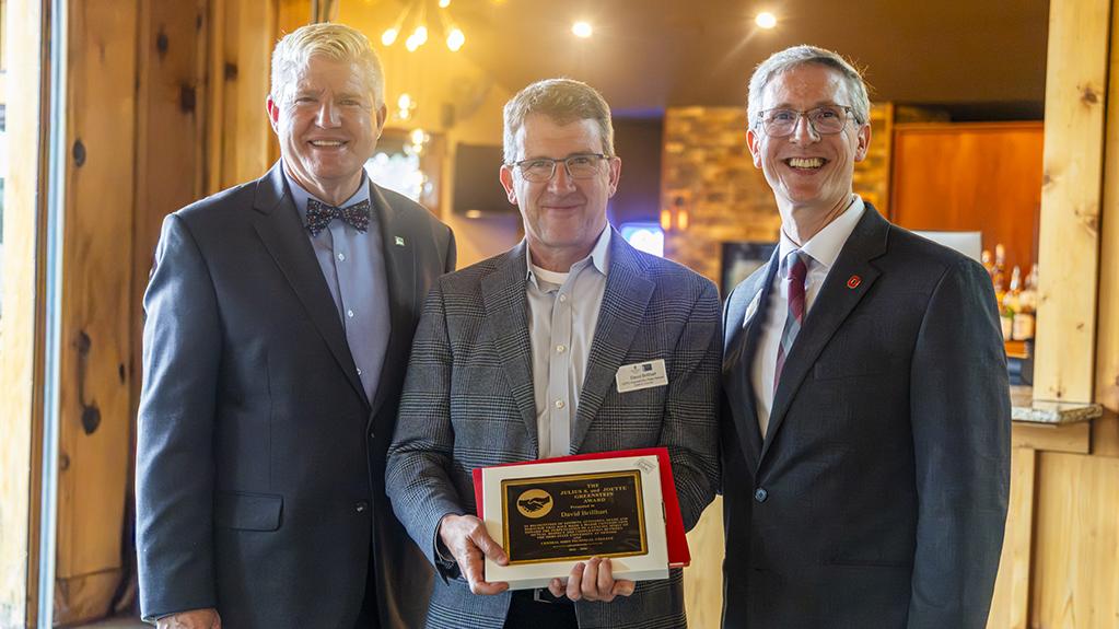 David Brillhart holds the Greenstein Award plaque he received while standing between COTC President John Berry and Ohio State Newark Dean and Director Matthew Smith.