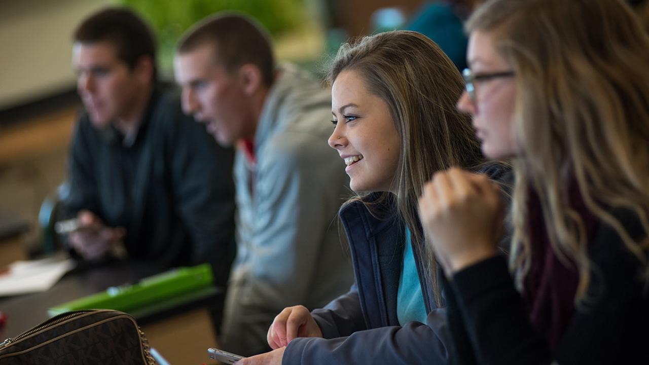 Four students smiling and engaged within a classroom setting