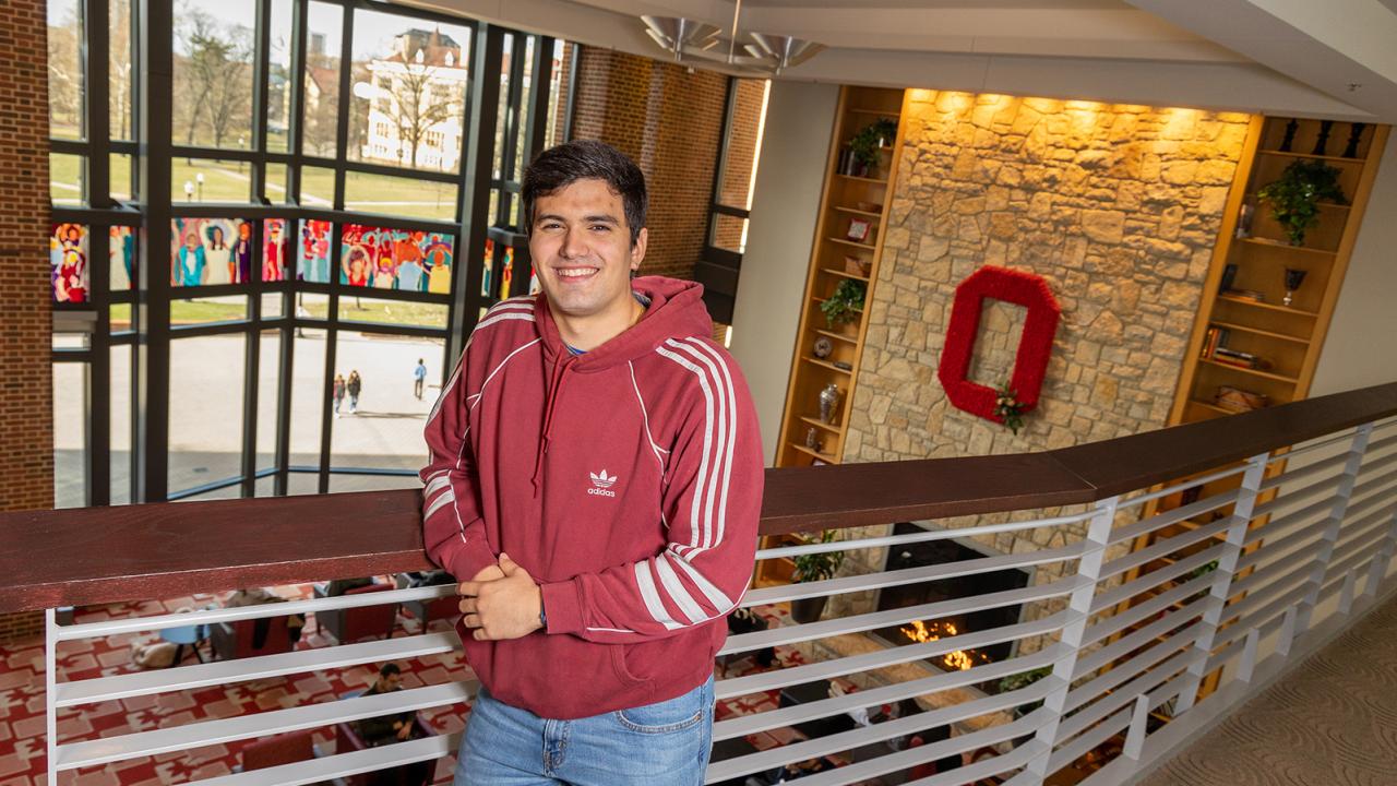 A student leans against a railing in the Ohio Union.