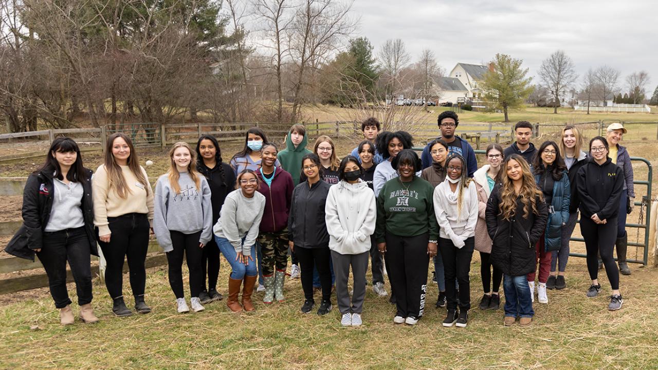 A group of students stands together on a farm which they visited as part of their academic enrichment.
