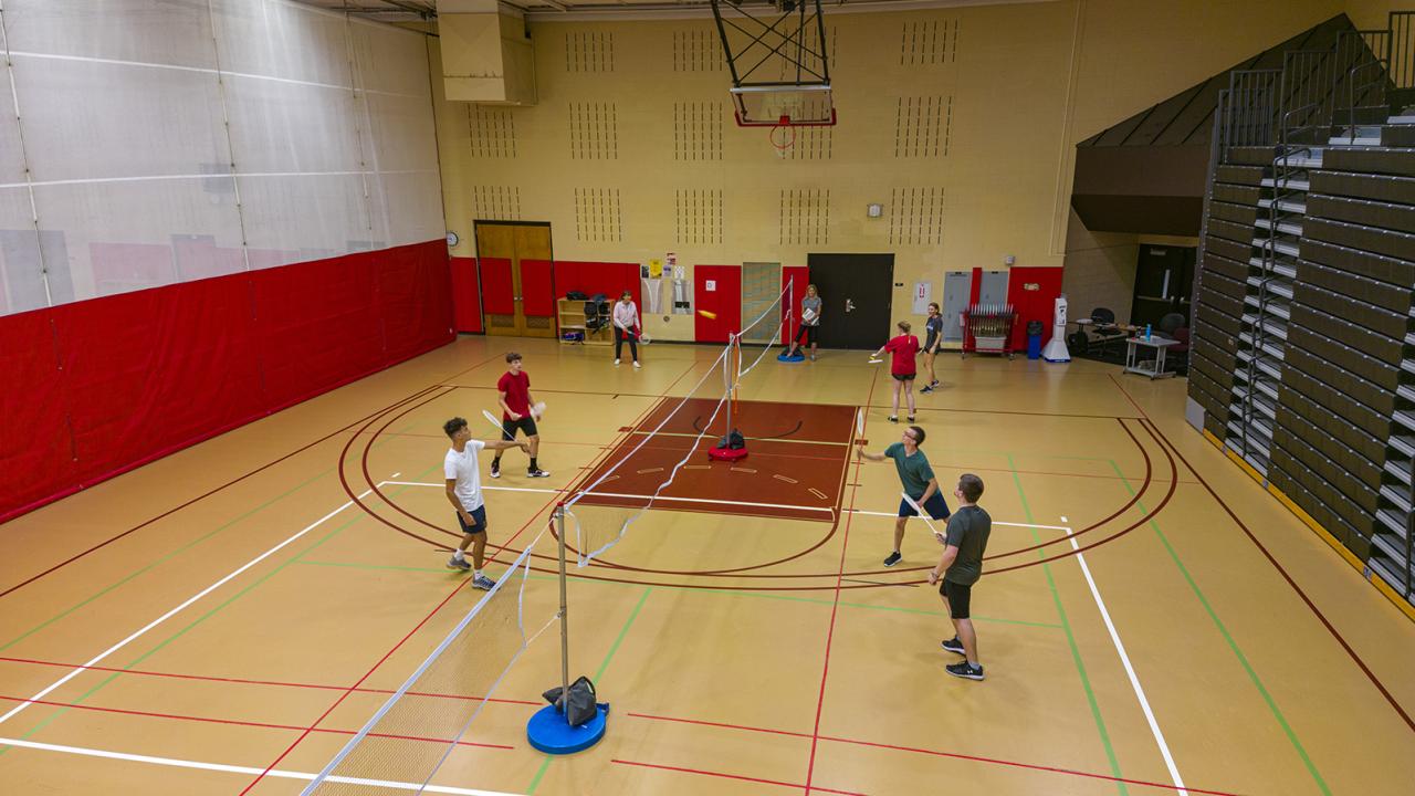 Students play badminton in the gymnasium. 