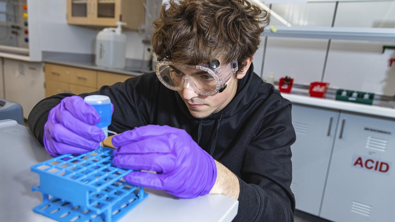 A student wearing safety goggles and gloves during lab. 