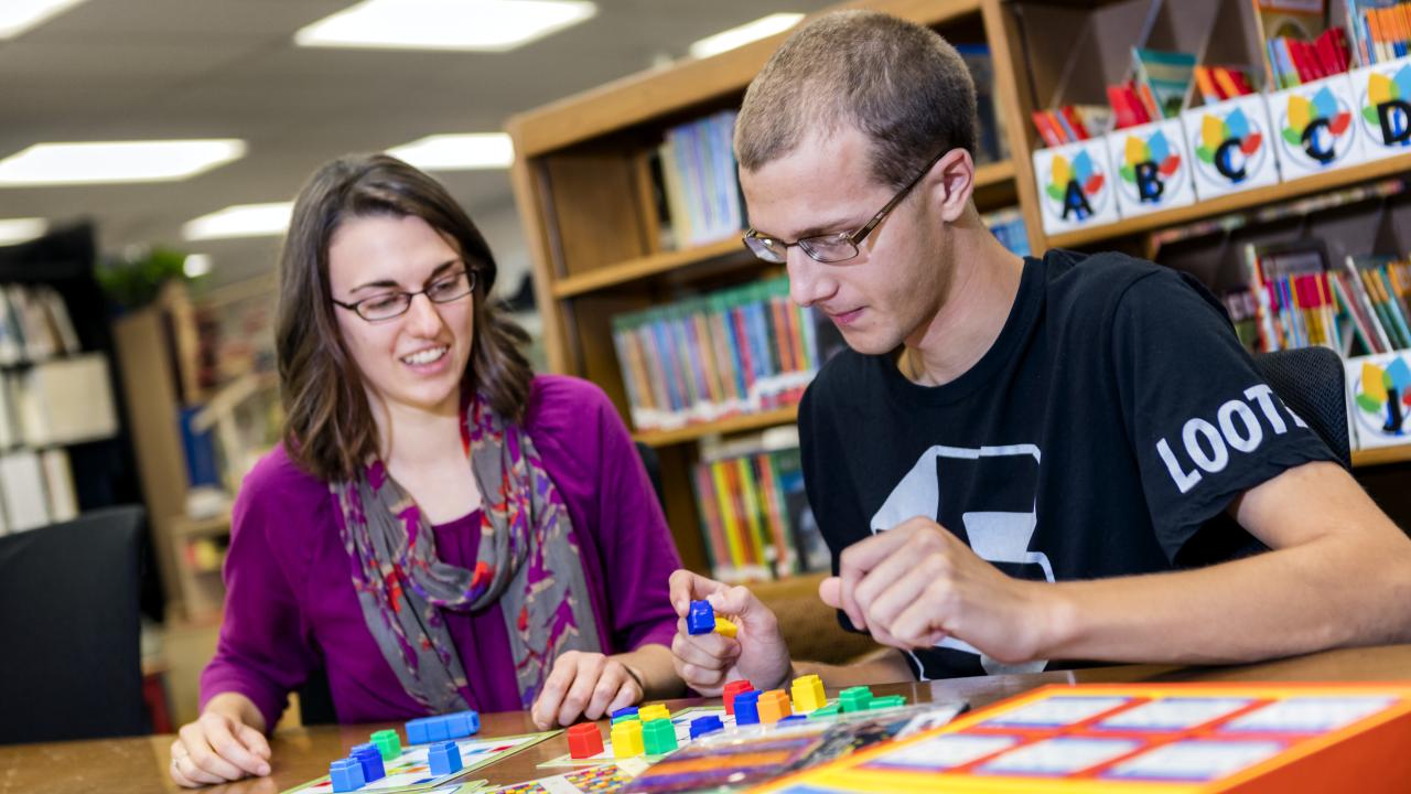 Two students use educational materials in the education curriculum center.